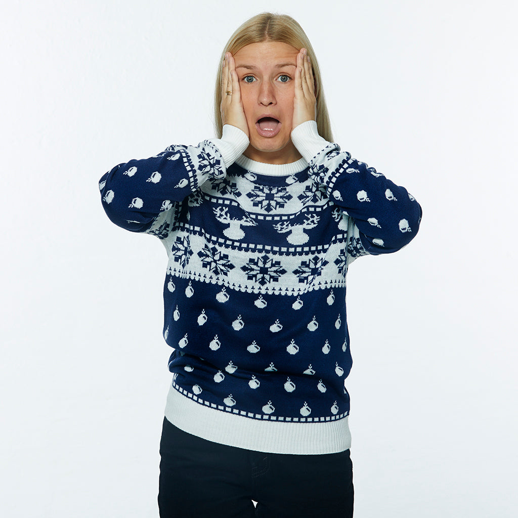 En dame poserer i en dybblå julesweater med julemønster.